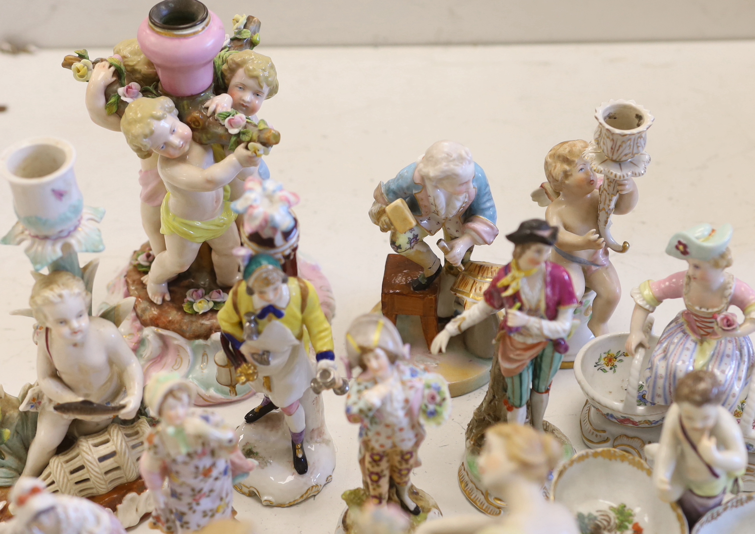 A collection of Continental porcelain figures, candleholders, table centres, some marked ‘AR’, cherubs, lovers, salesmen, tallest 20.5cm (15)